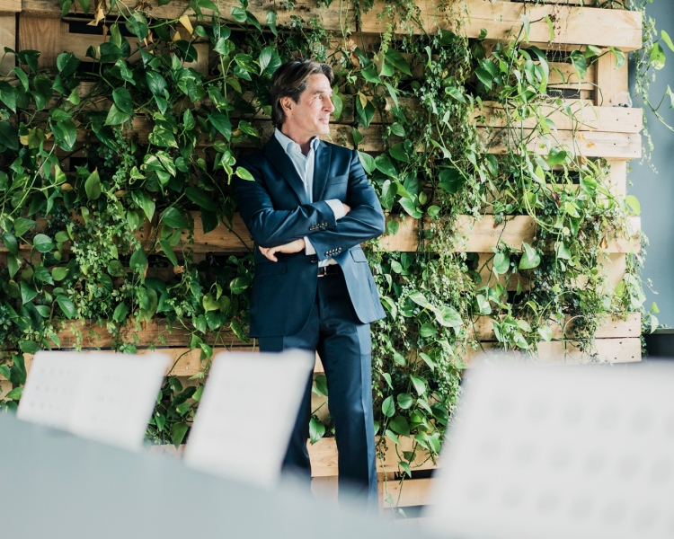 Businessmann vor einer Wand mit grünen Pflanzen