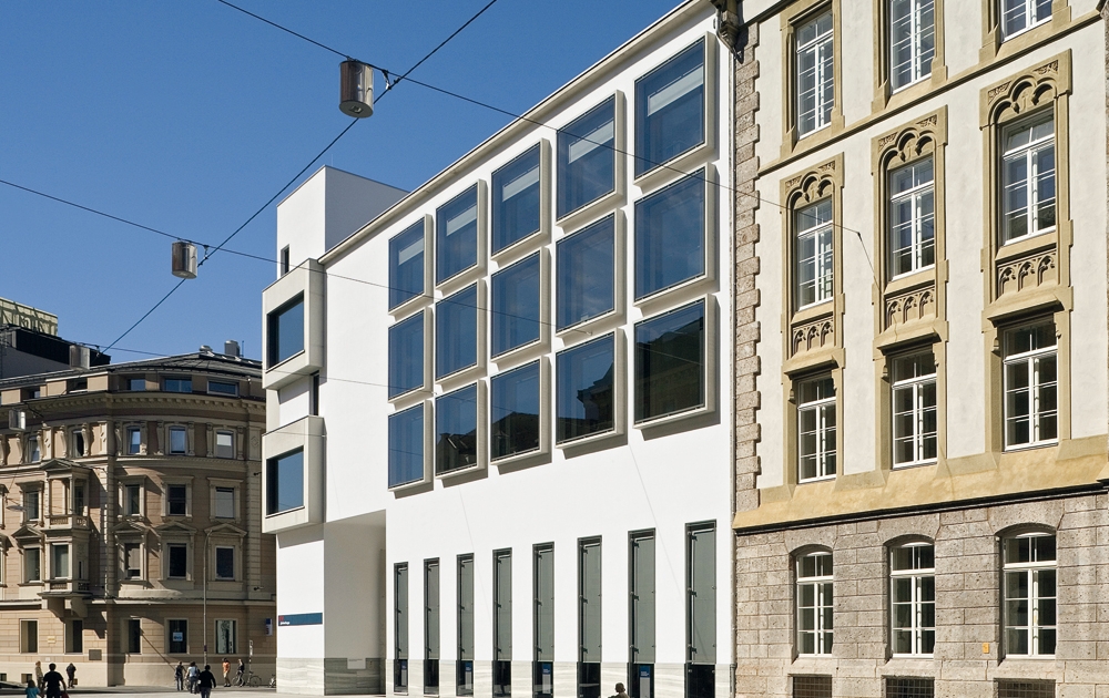 BTV Zentrale in Innsbruck Außenansicht: Weißes, modernes Gebäude mit vielen Fenstern zwischen zwei Altbau-Gebäuden