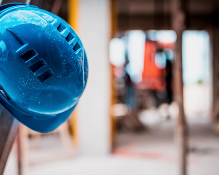 Ein blauer Helm hängt an einer Leiter vor einer Baustelle
