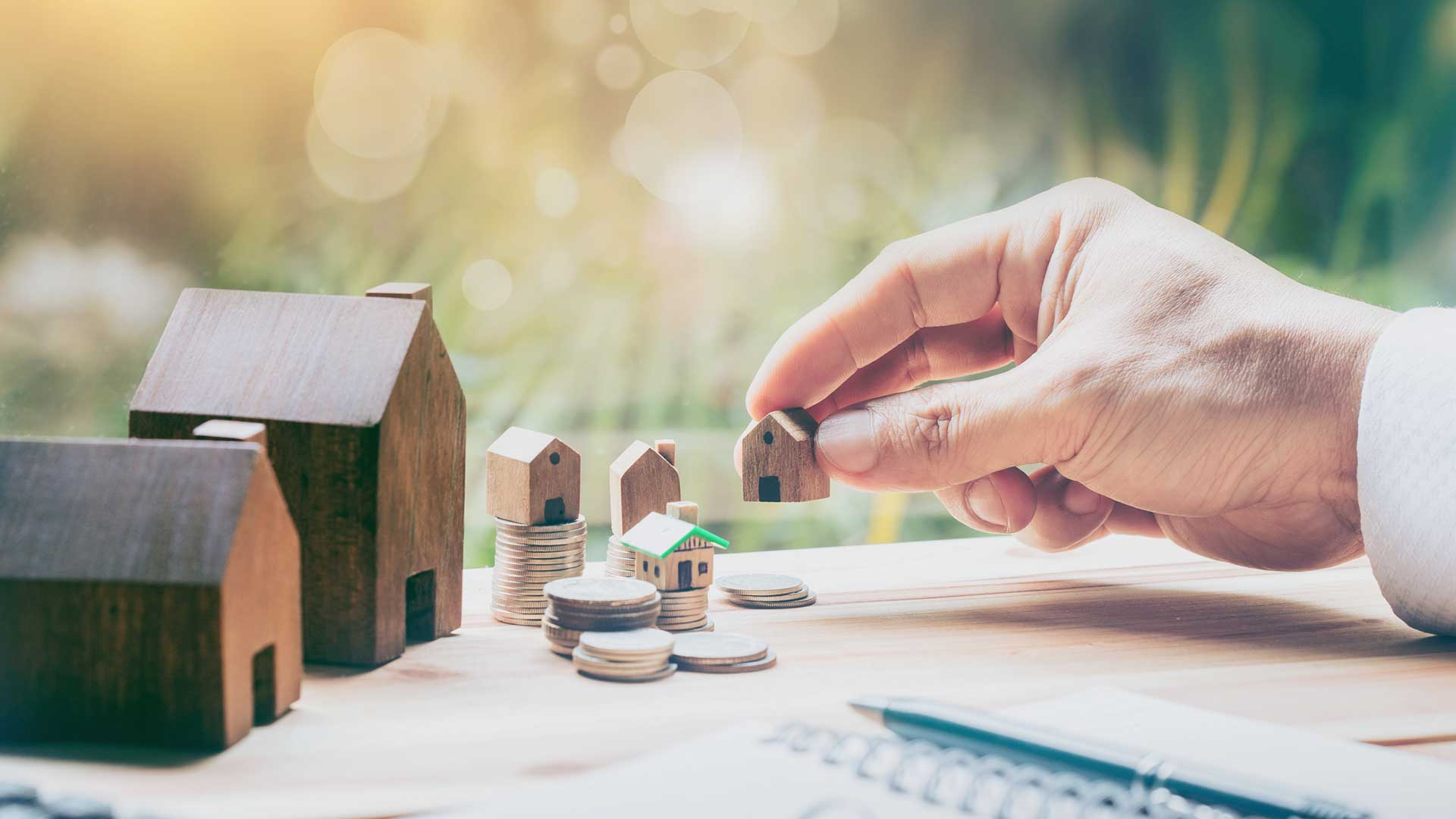 Mann stellt ein Miniatur-Haus auf den Tisch neben andere Miniatur-Häuser