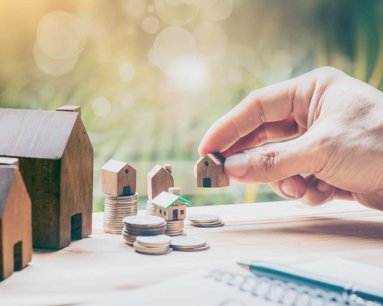 Mann stellt ein Miniatur-Haus auf den Tisch neben andere Miniatur-Häuser