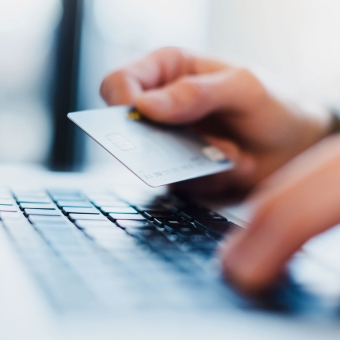Eine Person hält eine Debitkarte in der Hand und nutzt ein Keyboard