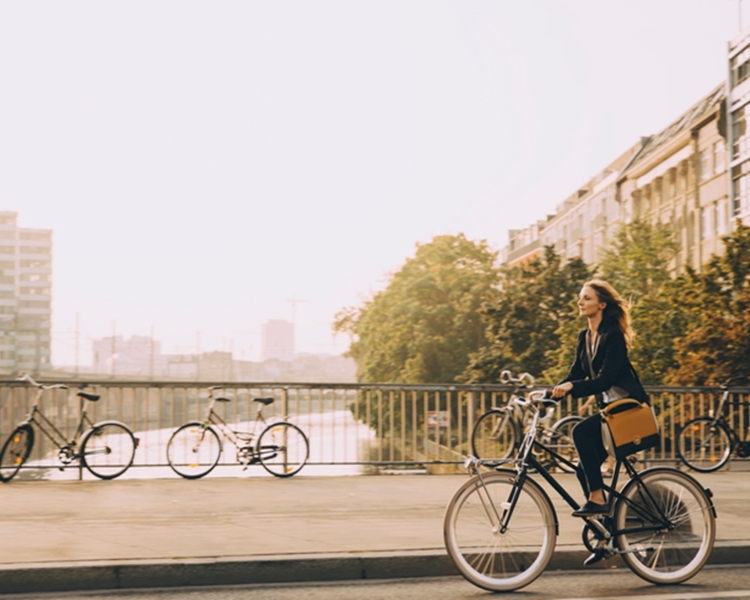 A woman rides a bike over a bridge in a city