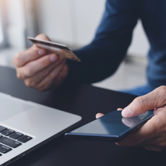Mann mit Kreditkarte am Laptop beim Online Bezahlen