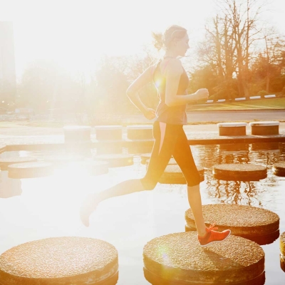 Frau joggt über Betonflächen auf einem kleinen Teich