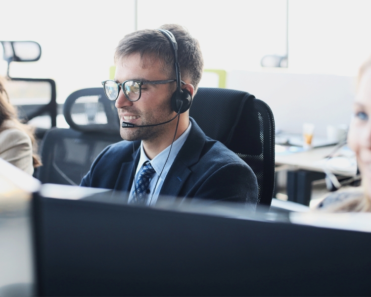 Drei Kundenbetreuer sitzen an ihren Computern mit Headsets ausgestattet