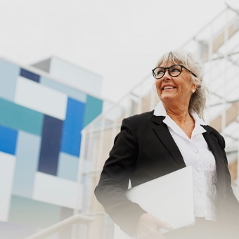 Eine Frau mit einer Brille hält ein Dokument in der Hand