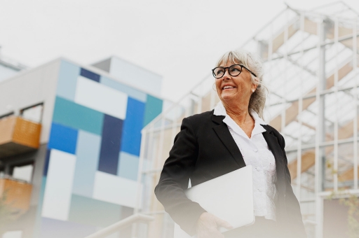 Eine Frau mit einer Brille hält ein Dokument in der Hand