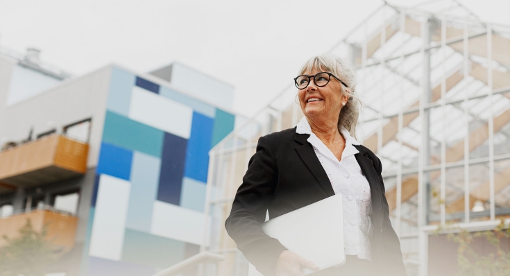 Eine Frau mit einer Brille hält ein Dokument in der Hand