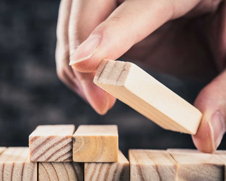 Frau legt ein Holzstück auf andere Holzstücke