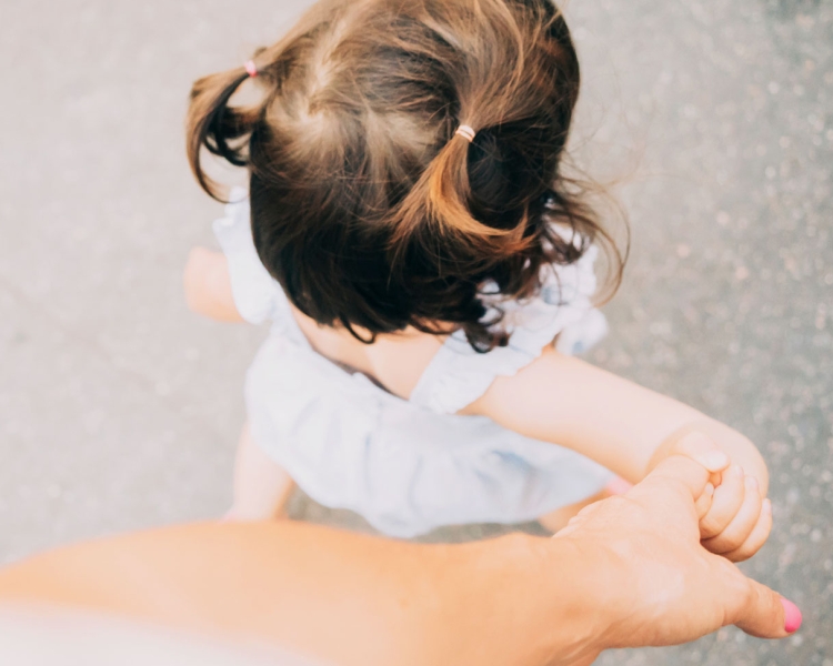 Mutter hält eine Hand von ihrer Tochter beim Gehen