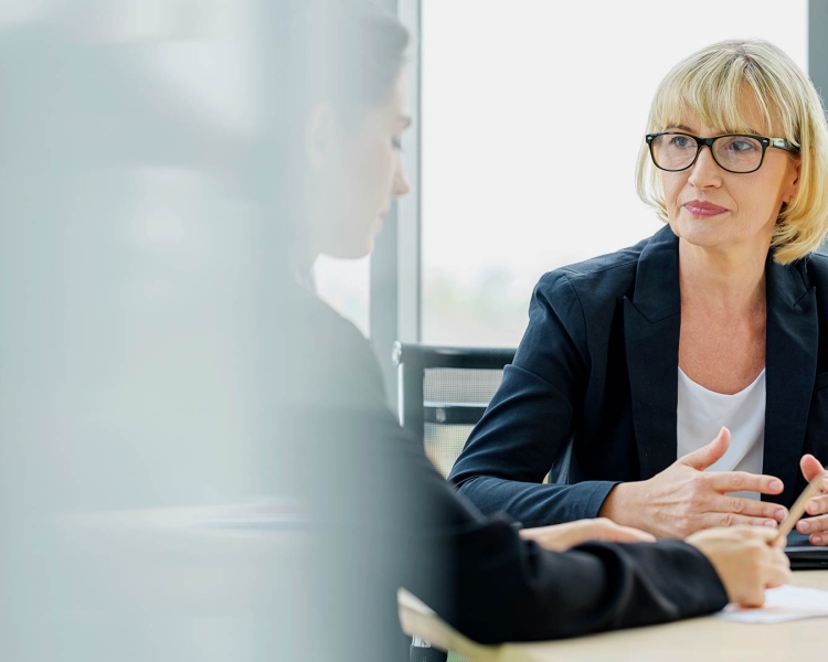 Two business women talking to each other while sitting at a table