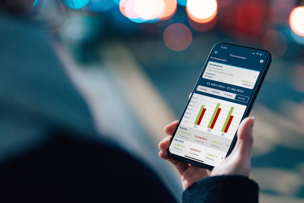 Ein Mann steht neben der Straße und blickt auf sein Smartphone