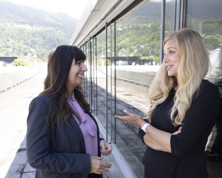 2 Frauen stehen auf einer Terrasse und sehen sich gegenseitig an