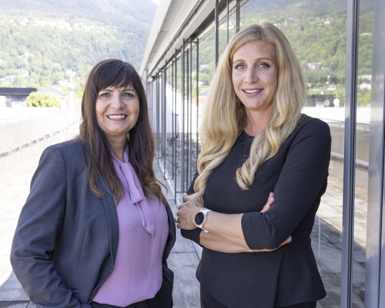 2 Frauen stehen auf einer Terrasse und sehen in die Kamera