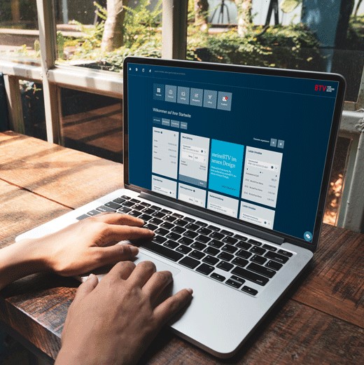 Mann sitzt am Schreibtisch und greift am Laptop auf sein Internetbanking zu