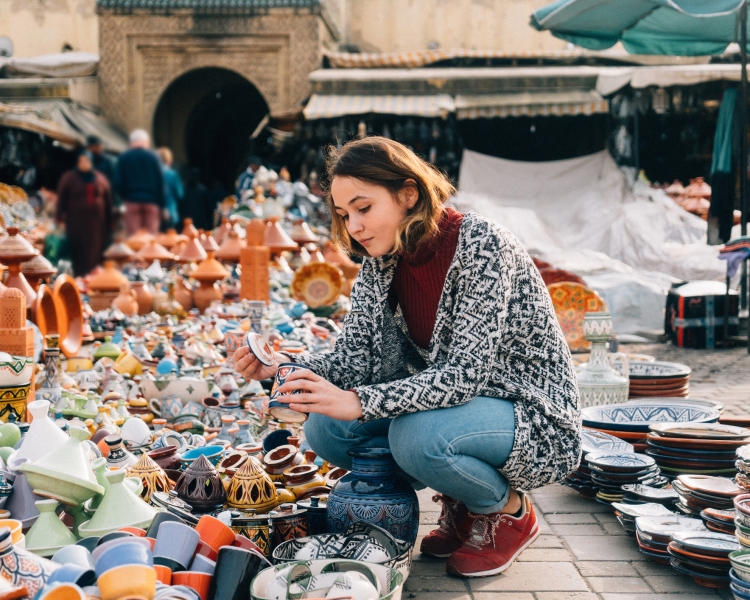Eine Frau begutachtet einen Gegenstand auf einem Markt