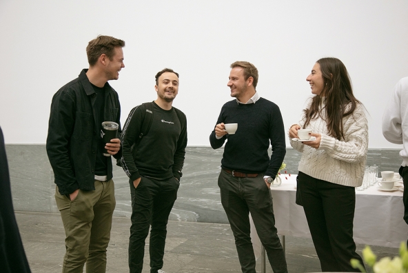 Eine Gruppe Personen stehen und trinken einen Kaffee