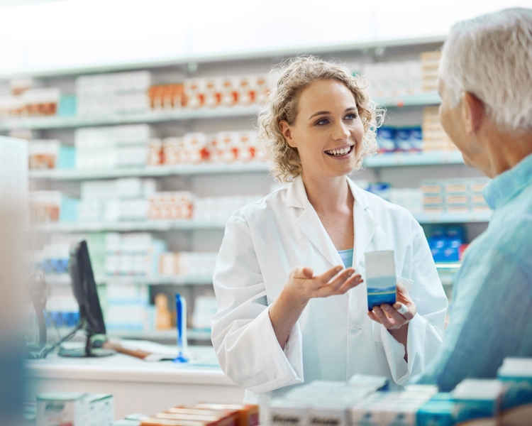 Pharmazeutin präsentiert ein Medikament und berät dabei einen Kunden an der Tara