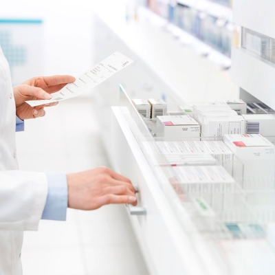 Pharmazeut öffnet Apothekenschrank mit Medikamenten