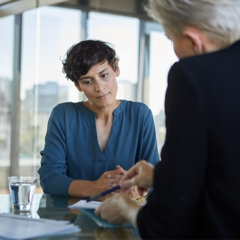 Zwei Frauen sitzen an einem Tisch und betrachten Dokumente