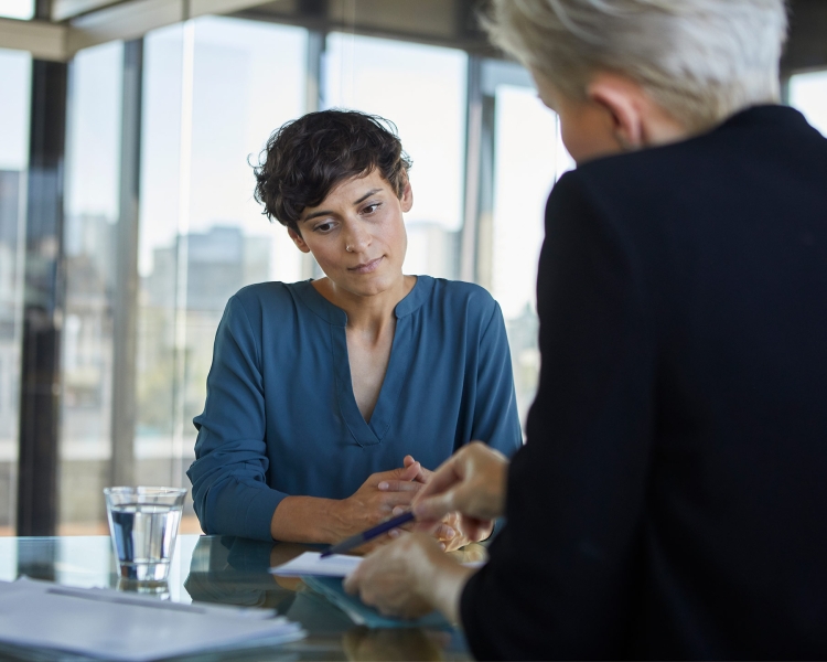Zwei Frauen sitzen an einem Tisch und betrachten Dokumente