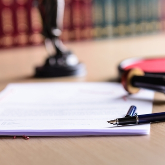 Verträge liegen in Kanzlei von Notar am Tisch mit Büchern im Hintergrund