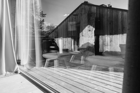 Blick aus einem Hotelzimmer auf eine Außendusche vor einem Holzhaus