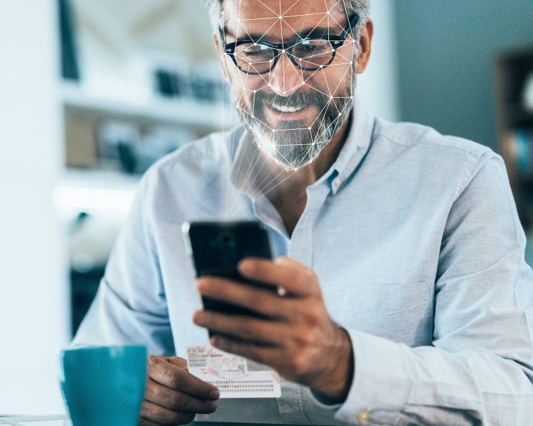 Ein Mann blickt auf sein Smartphone, um sich via Gesichtserkennung anzumelden