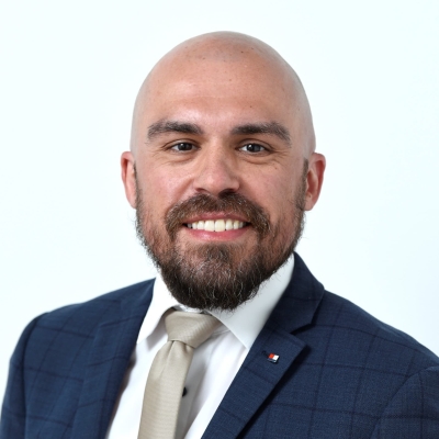 Marco Tamalio trägt einen blau karierten Anzug, ein weißes Hemd und eine beige Krawatte