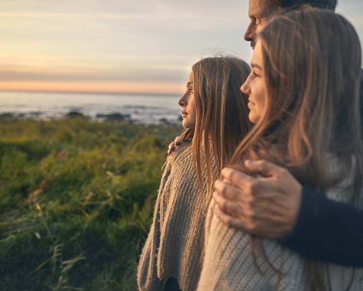 Vater schaut mit seinen beiden Töchtern in den Sonnenaufgang