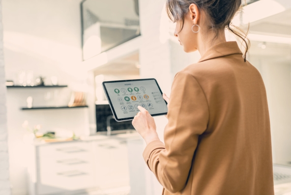 Frau befindet sich zuhause und bedient via Tablet eine Smart Home App.