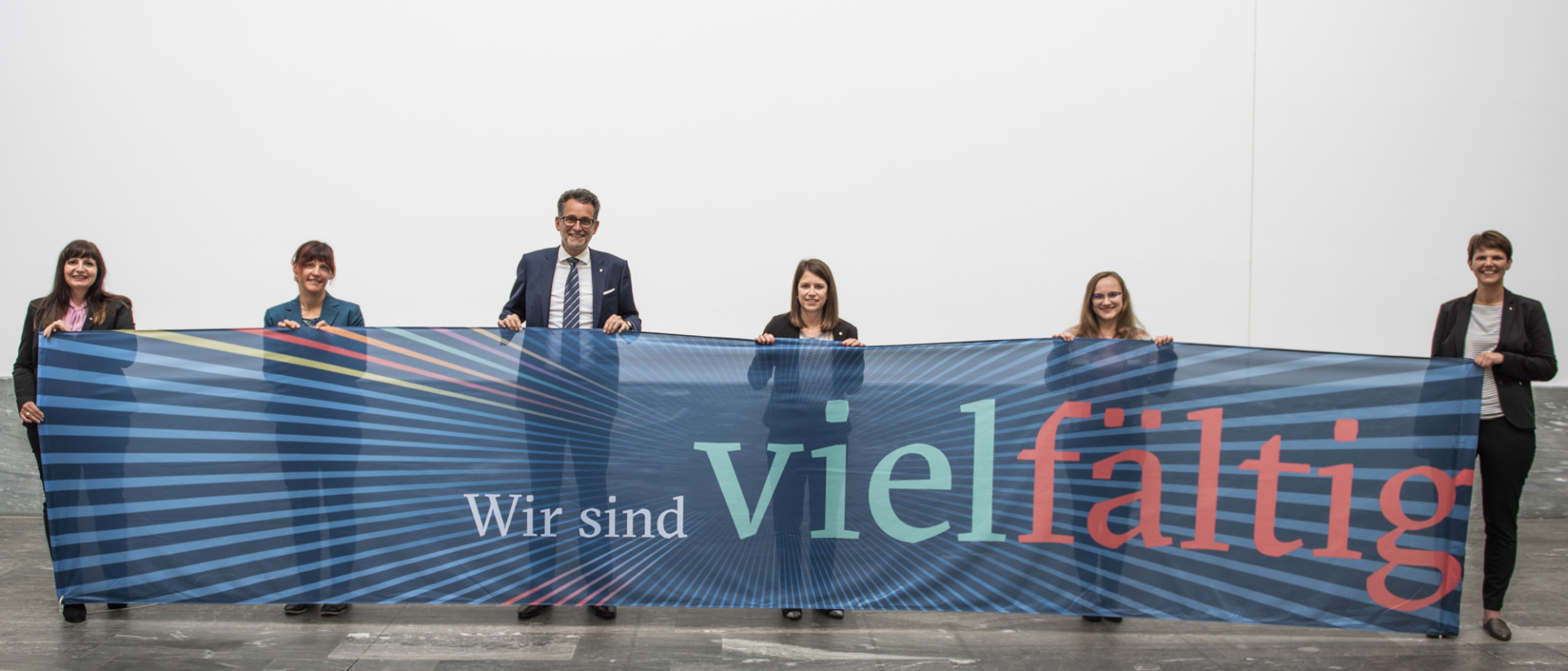 6 Mitarbeiter*innen mit einem BTV vielfältig Banner