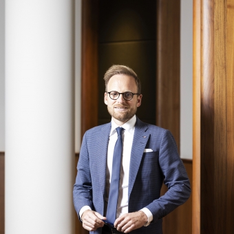 Ein Mann in einem blauen Anzug lächelt in die Kamera.