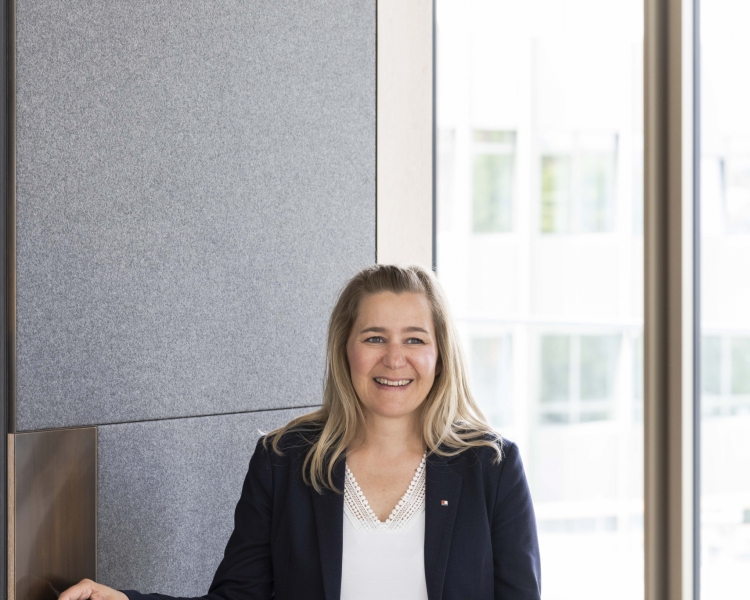 Anja Mell, Mitarbeiterin BTV Stuttgart, vor einer gestreiften Tapete.