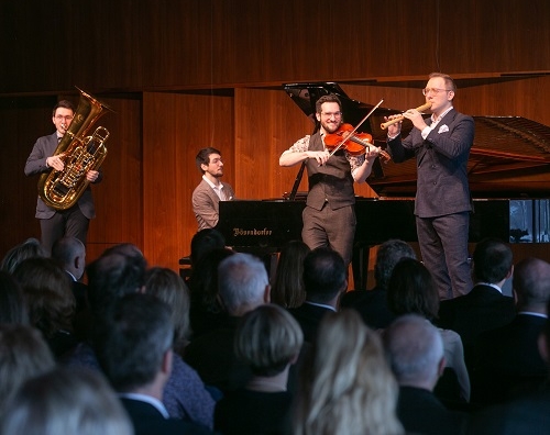 Personen mit einem Instrument stehen auf einer Bühne