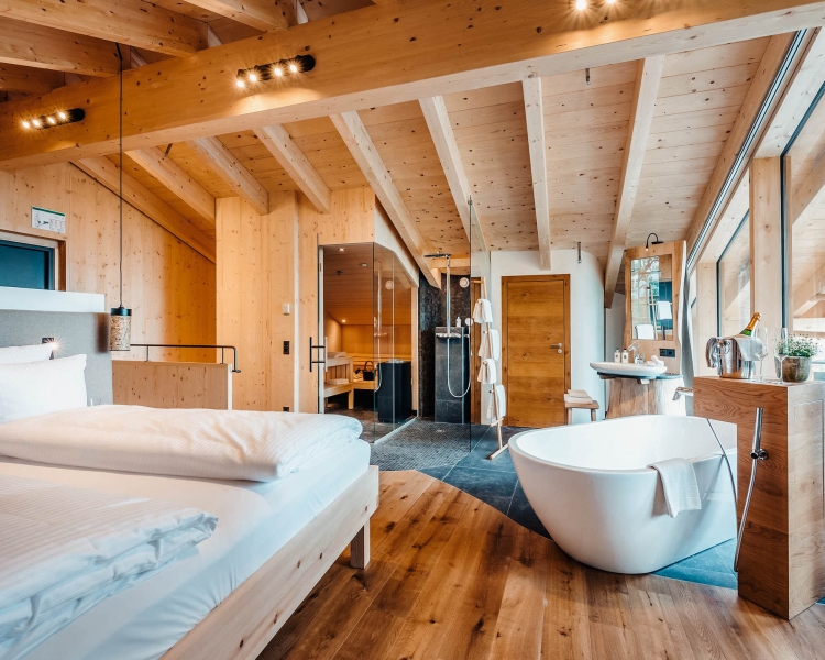 Hotelzimmer aus Holz mit Bett und freistehender Badewanne.