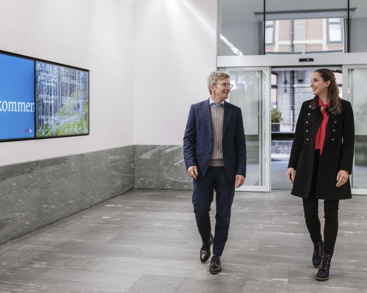 Mann und Frau spazieren durch ein Bankfiliale.
