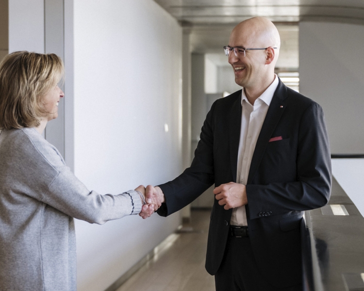 Eine Frau und ein Mann geben sich lächelnd die Hand.