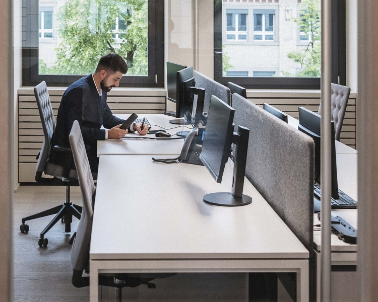 Ein Mann in Anzug sitzt am Schreibtisch und notiert etwas.