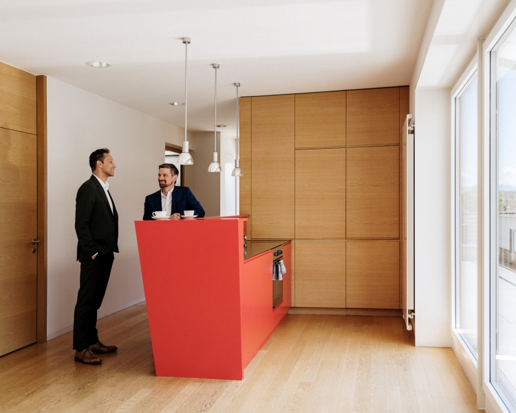 Zwei Männer unterhalten sich in einer Küche in der Farbe Rot.