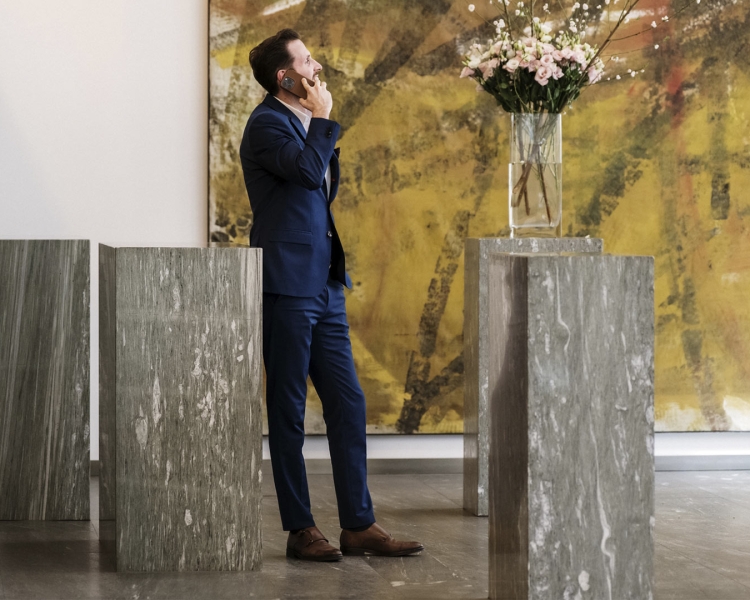 Ein Mann in Anzug telefoniert und schaut sich Blumen an.