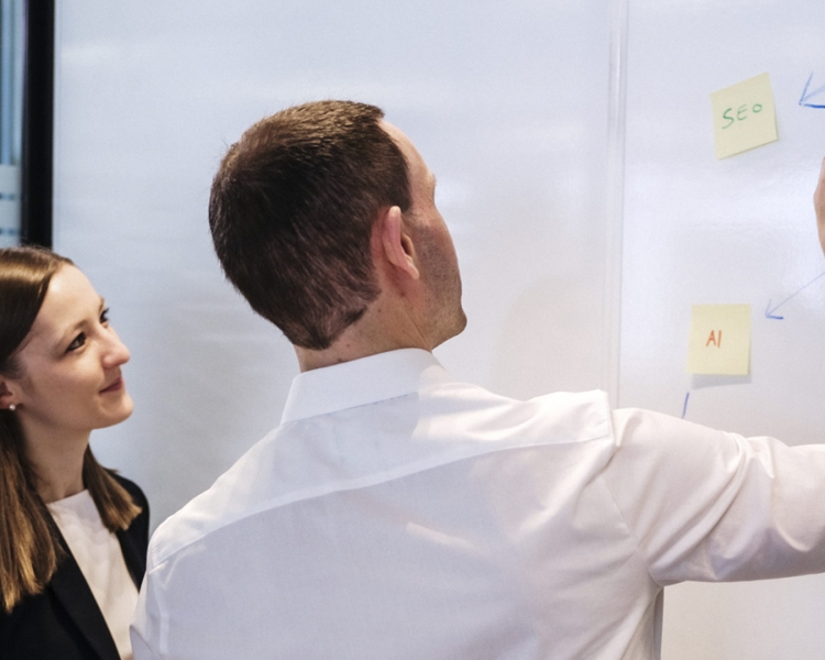 Eine Person zeigt etwas auf einem Whiteboard.