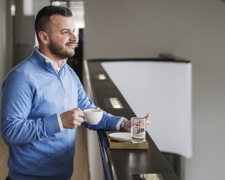 Ein Mann schaut in die Ferne und trinkt einen Kaffee.