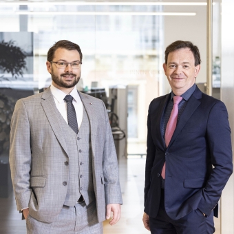 Benjamin Telser und Georg Lehmann im Anzug vor einer Glaswand in einem Büro