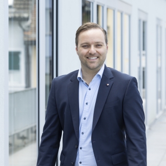 Mann in einem blauen Anzug lächelt in die Kamera.