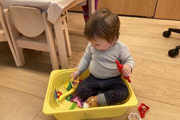Ein Kind spielt in einer Plastik Box mit Spielsachen