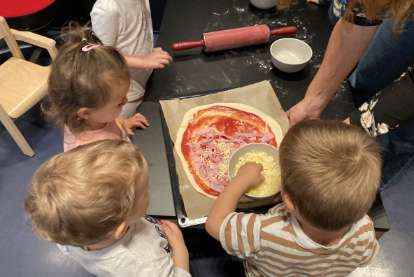 4 Kinder bereiten gemeinsam eine Pizza vor