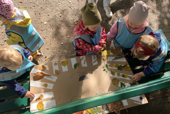 5 Kinder spielen in einem Wald und sammeln Blätter