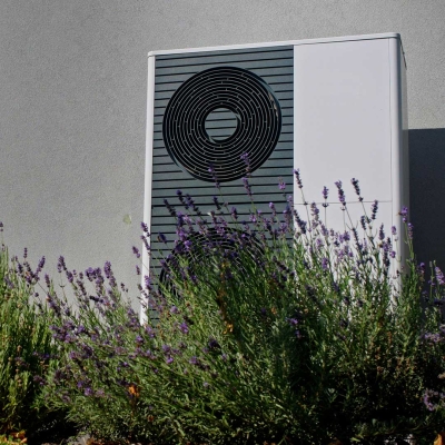 Ein Wärmepumpe mit Pflanzen im Vordergrund